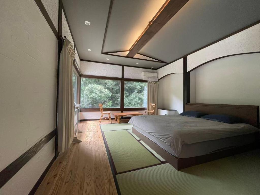 une chambre avec un lit et une grande fenêtre dans l'établissement 天然温泉旅館 繁花荘せせらぎ, à Kirishima