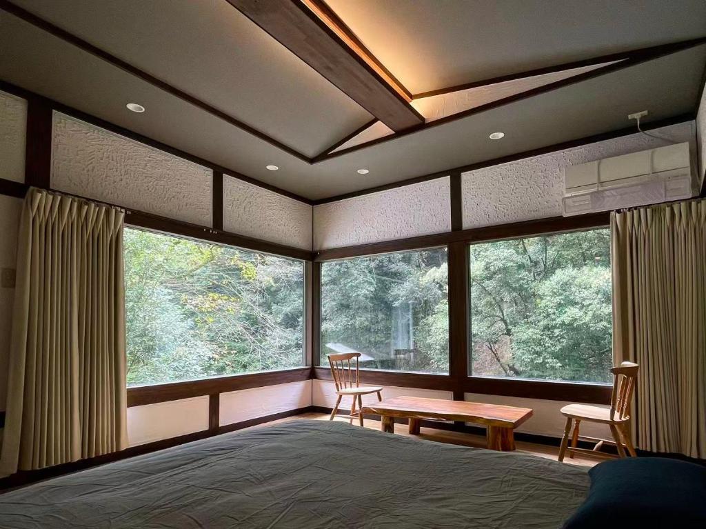 une chambre avec un lit et une grande fenêtre dans l'établissement 天然温泉旅館 繁花荘せせらぎ, à Kirishima