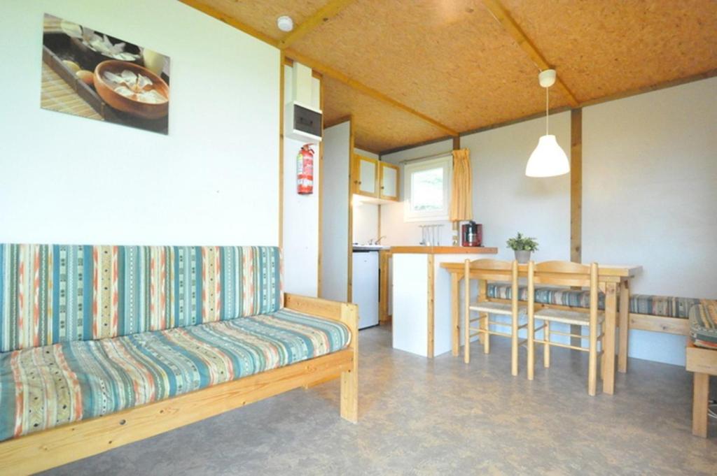 un salon avec un canapé et une cuisine avec une table dans l'établissement Camping Domaine Papillon, à Reyrevignes