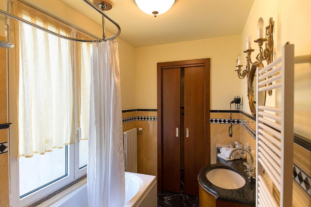 une salle de bain avec une baignoire, un lavabo et une fenêtre dans l'établissement Hotel Serenella, à Sirmione