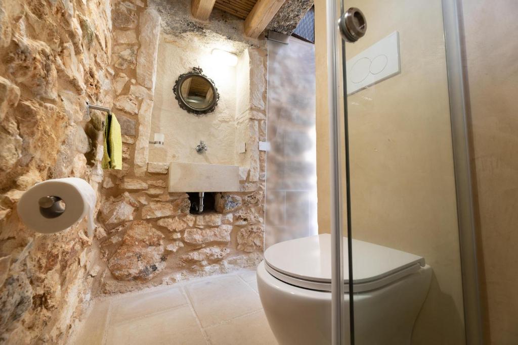 La salle de bains est pourvue de toilettes et d'un mur en pierre. dans l'établissement Villa Platino, à Torre Vado 30 autres photos