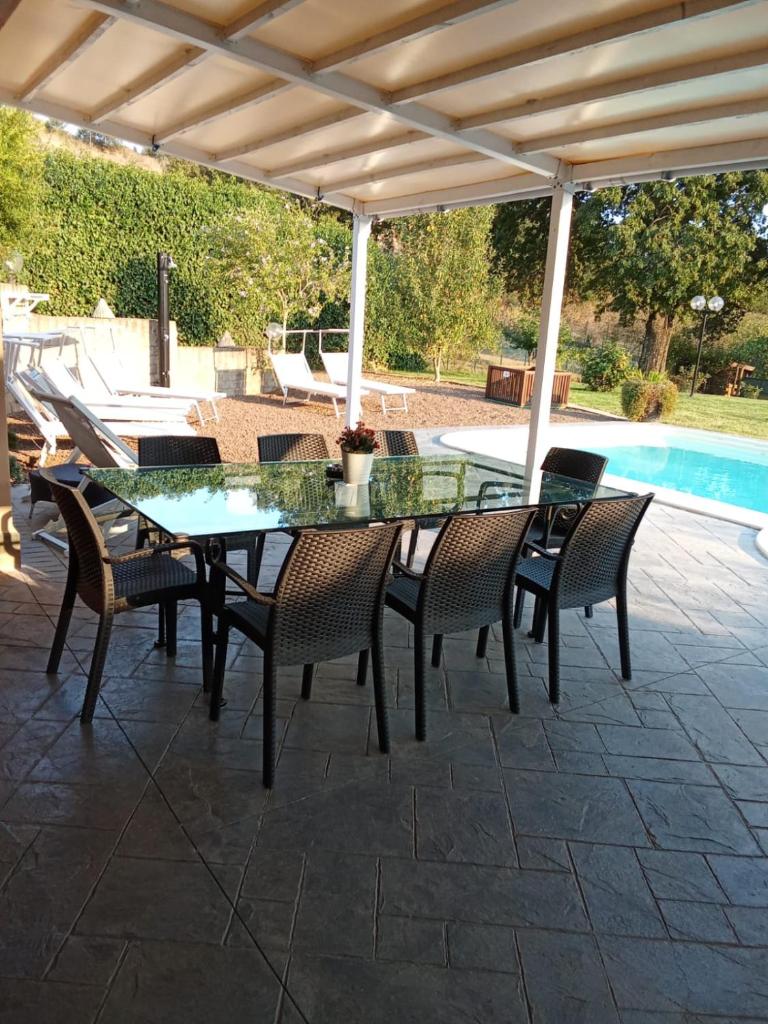 une table et des chaises en verre sur une terrasse avec piscine dans l'établissement Villa Panorama Pool & Garden, à Trevignano Romano 59 autres photos