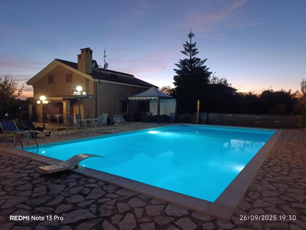 une piscine bleue avec une maison en arrière-plan dans l'établissement Villa Anna, à Genzano di Roma