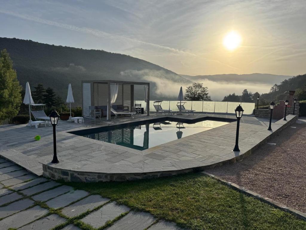 une piscine avec un coucher de soleil en arrière-plan dans l'établissement Villa Marinelli in Toscana, à Castel Focognano