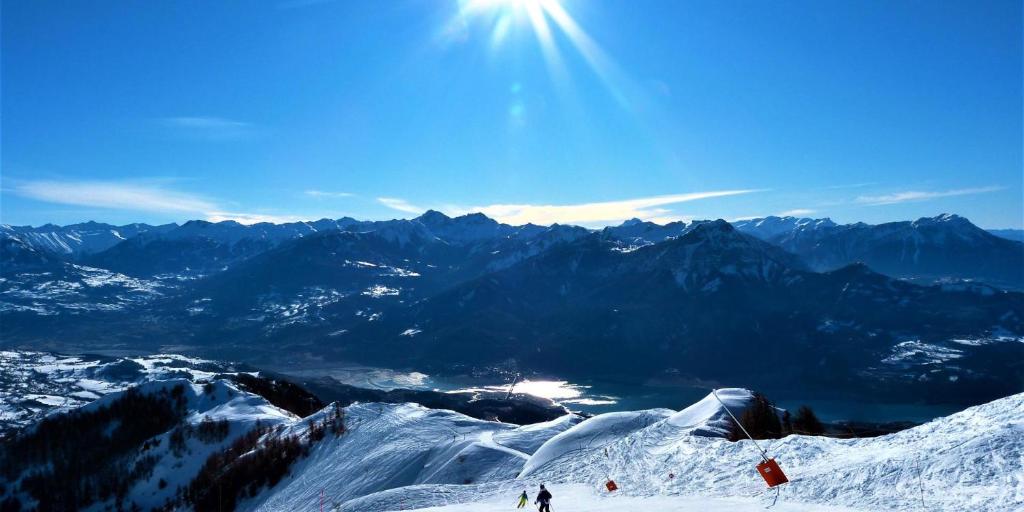 deux personnes skiant au sommet d'une montagne enneigée dans l'établissement Duplex dans chalet au coeur de la station, à Réallon