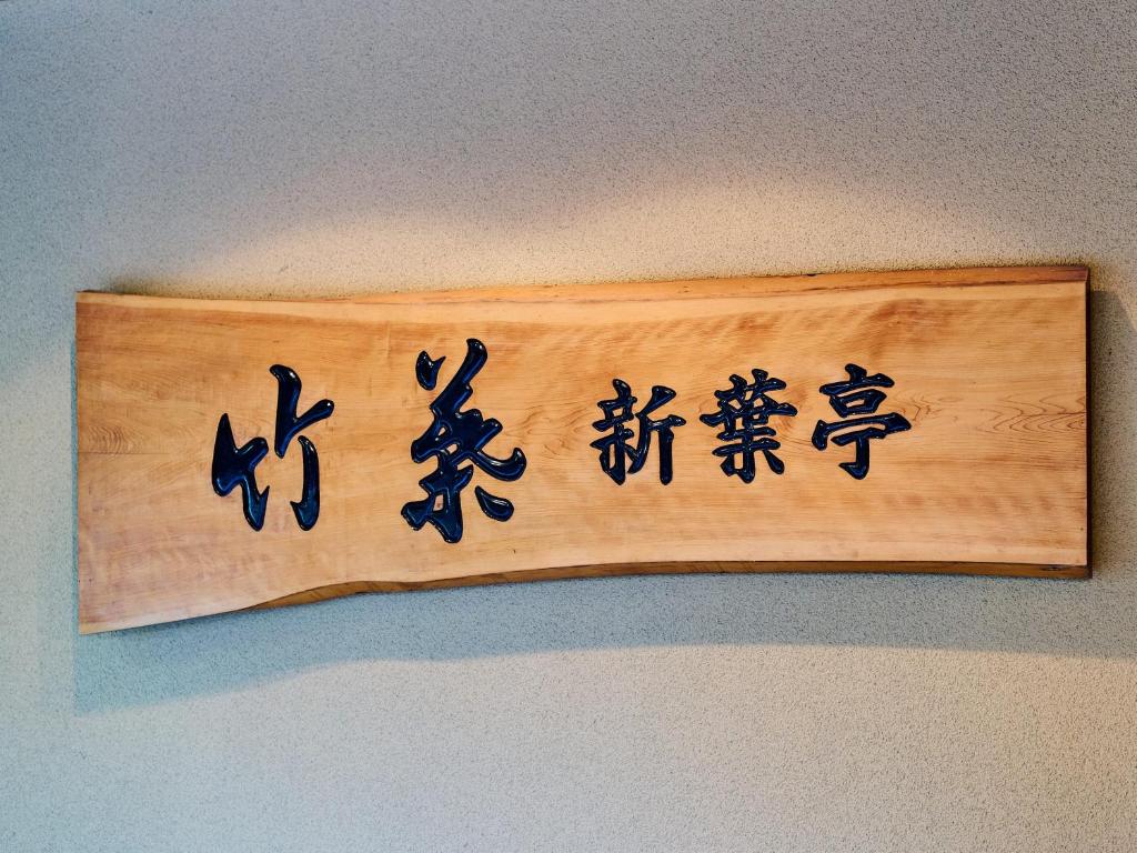 un panneau en bois avec des écrits chinois sur un mur dans l'établissement Tabist Chikuba Shinyotei Hakodate Yunokawaonsen, à Hakodate