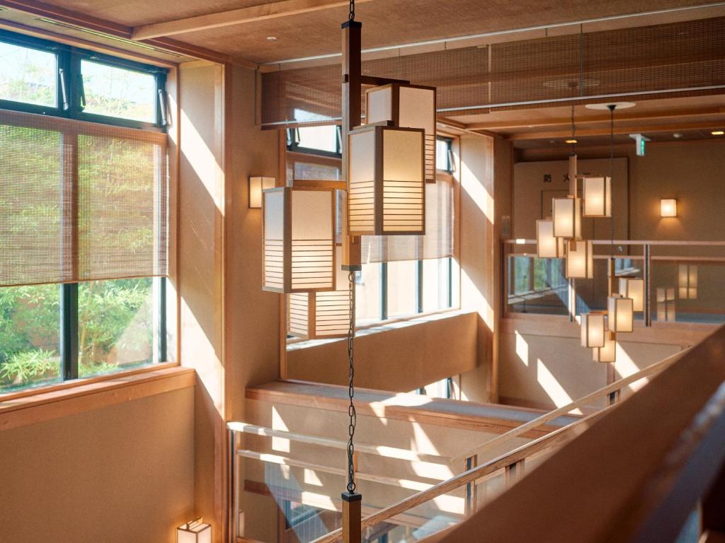 un couloir avec des escaliers et des fenêtres dans un bâtiment dans l'établissement Tabist Chikuba Shinyotei Hakodate Yunokawaonsen, à Hakodate
