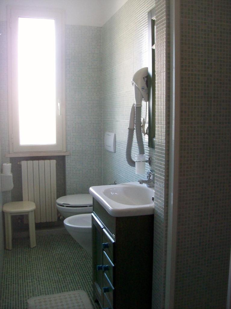 une salle de bain avec un lavabo et des toilettes et une fenêtre dans l'établissement Hotel Sole, à Giulianova