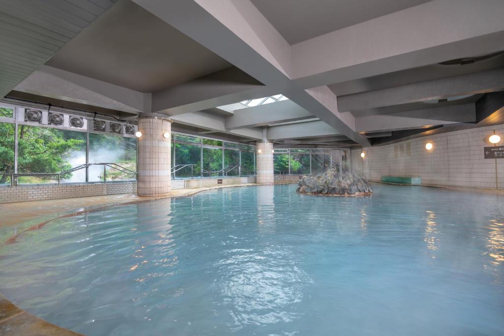 une grande piscine avec de l'eau bleue dans un immeuble dans l'établissement Kirishima Kokusai Hotel, à Kirishima
