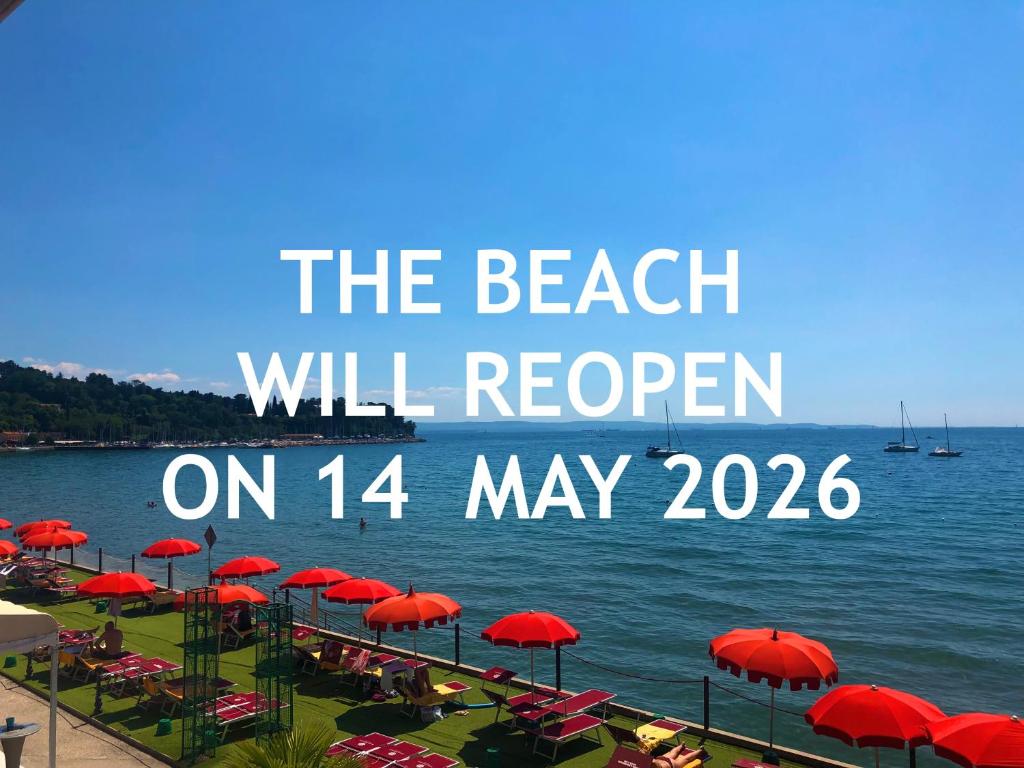 une plage avec des parasols rouges et les mots « la plage rouvrira le » dans l'établissement Hotel Riviera & Maximilian's, à Trieste