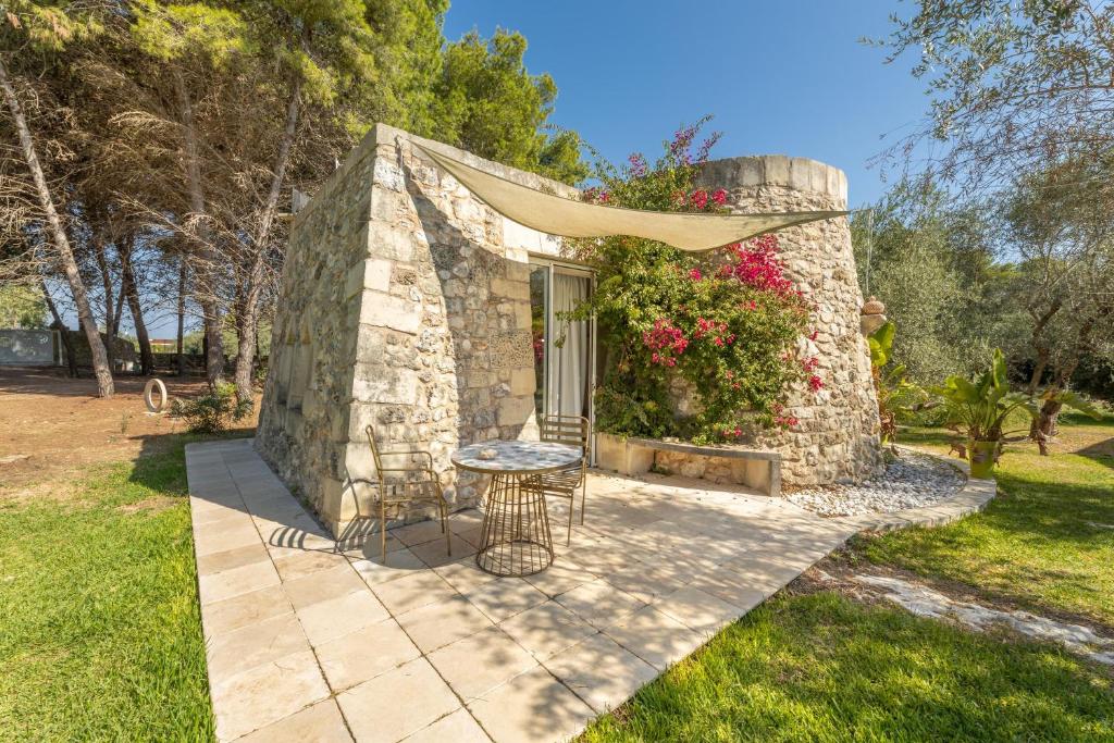 une petite maison en pierre avec une table dans une cour dans l'établissement Tenuta Arcàdia, à Cursi