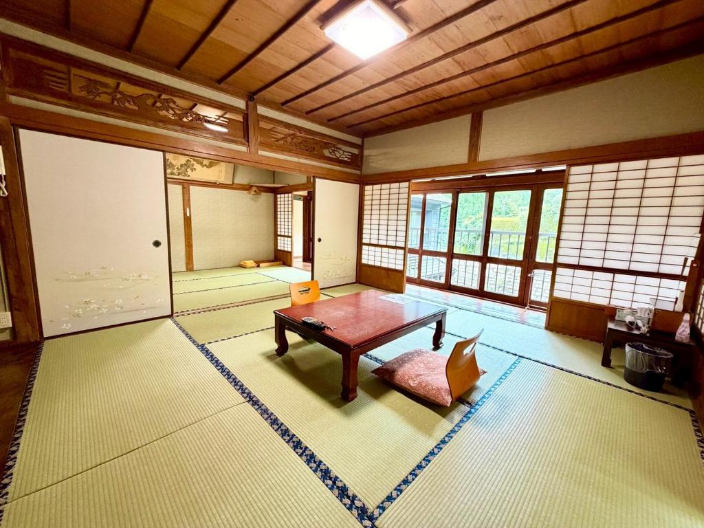 une pièce avec une table dans une pièce avec des fenêtres dans l'établissement Takaosou, à Yufu