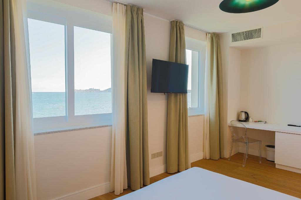 une chambre avec un lit et une fenêtre avec l'océan dans l'établissement Villa Maria Teresa Boutique Hotel, à Formia