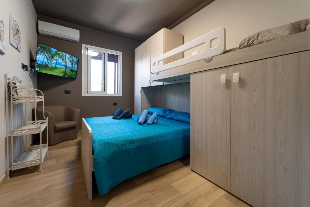 Cette petite chambre comprend un lit bleu et une télévision. dans l'établissement Villa Tea con piscina a pochi passi dal mare, à Fontane Bianche 37 autres photos