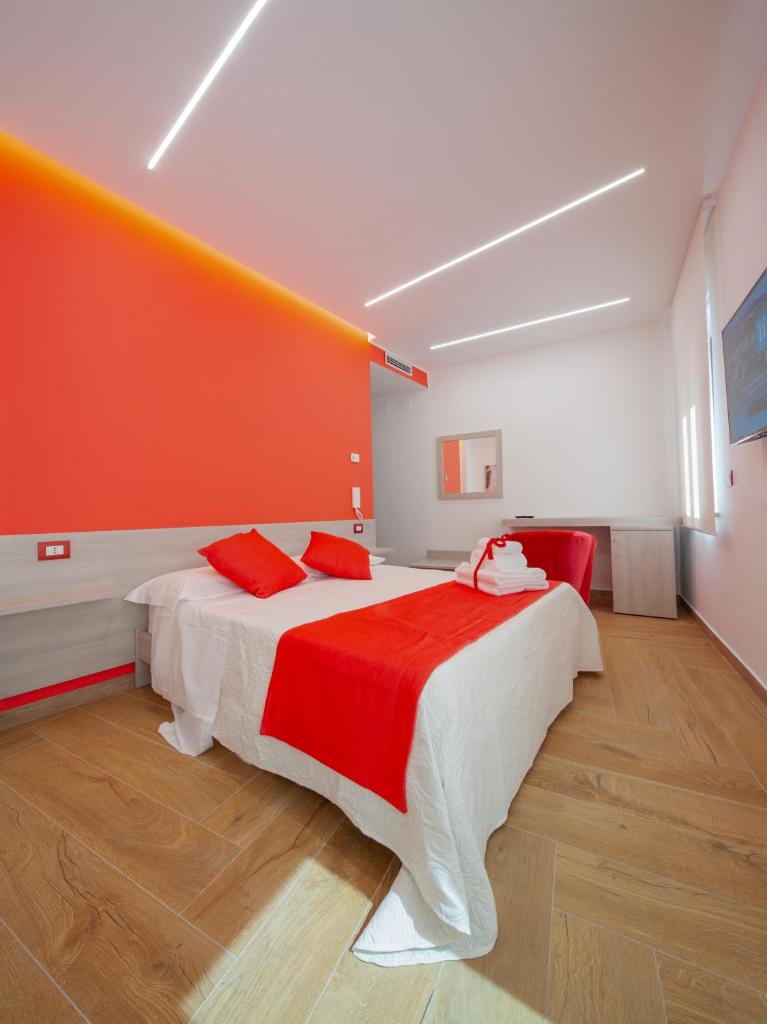 une chambre avec un grand lit avec un mur orange dans l'établissement Palazzo Fiorentini Charme Hotel, à Cariati