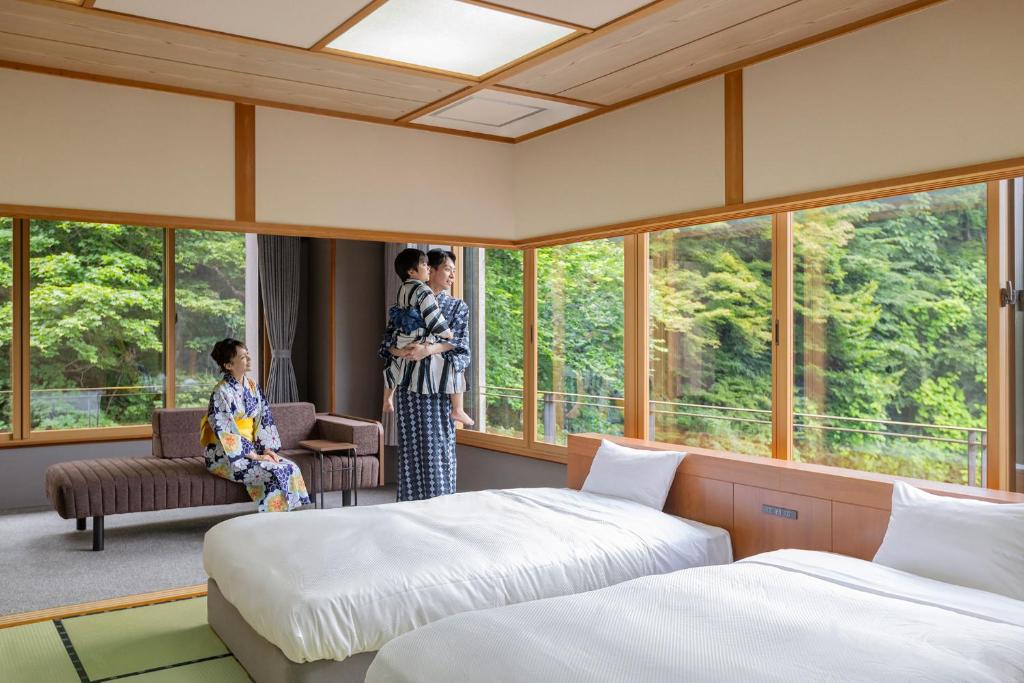 deux femmes en kimono debout dans une pièce avec deux lits dans l'établissement Ooedo Onsen Monogatari Premium Ikaho, à Shibukawa