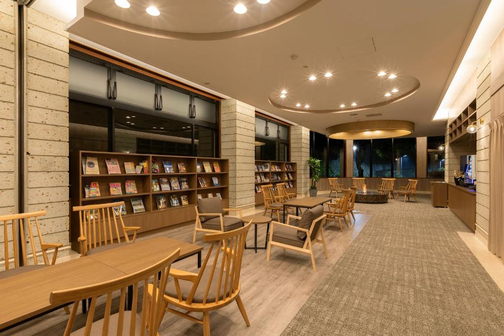 une bibliothèque avec des tables, des chaises et des livres en bois dans l'établissement Ooedo Onsen Monogatari Premium Ikaho, à Shibukawa