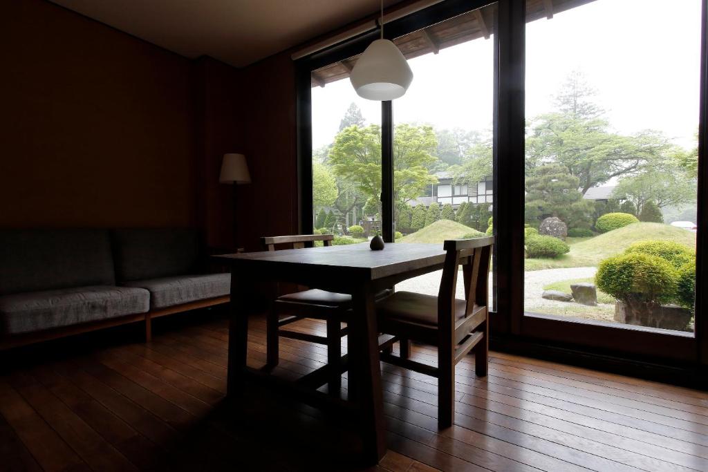 une salle à manger avec une table et des chaises et une grande fenêtre dans l'établissement Itamuro Onsen Daikokuya, à Nasushiobara