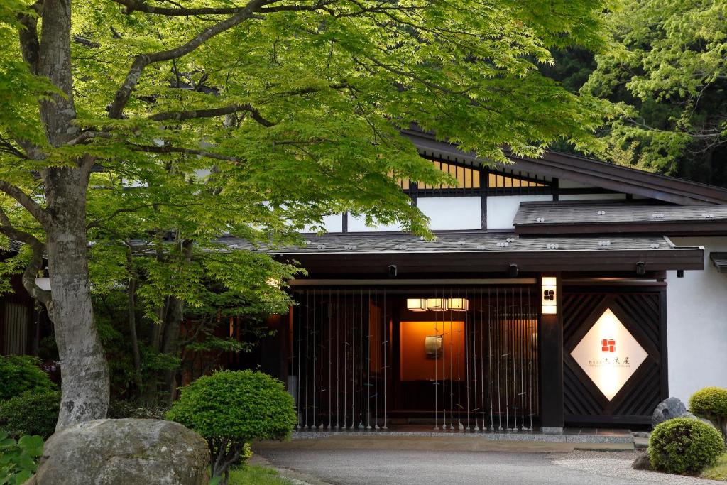 une maison japonaise avec un arbre devant elle dans l'établissement Itamuro Onsen Daikokuya, à Nasushiobara