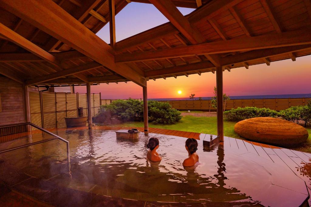 - deux filles assises dans un bain à remous pour admirer le coucher du soleil dans l'établissement Ooedo Onsen Monogatari Premium Shiomiso, à Murakami
