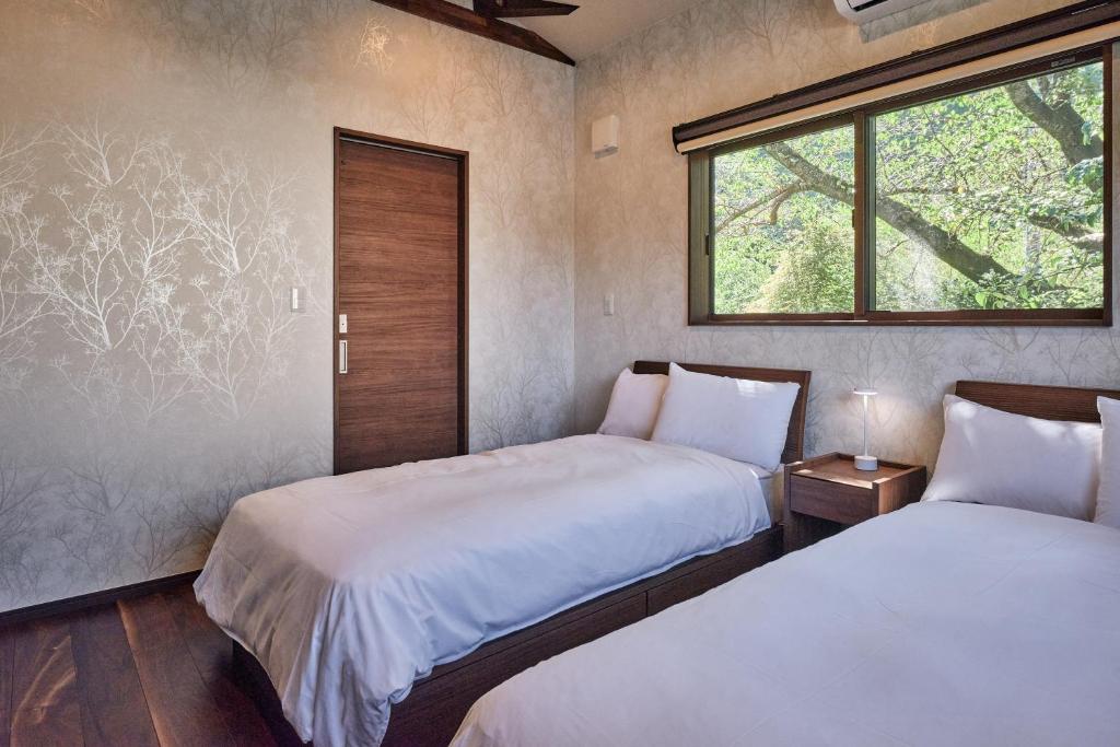 deux lits dans une chambre avec une fenêtre dans l'établissement Nunohiki Onsen Komoro, à Komoro 78 autres photos