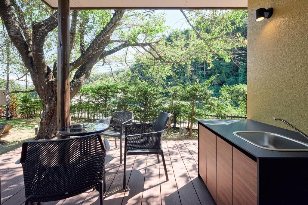 d'une terrasse avec une table, des chaises et un arbre. dans l'établissement Nunohiki Onsen Komoro, à Komoro