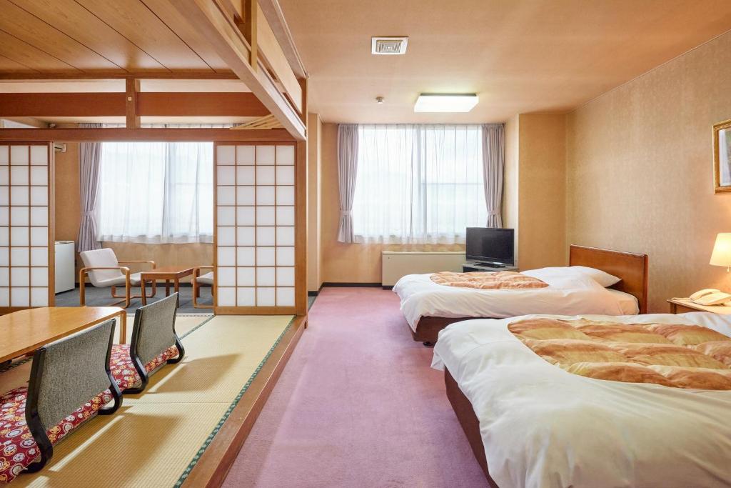 Cette chambre comprend 3 lits et une table. dans l'établissement Nunohiki Onsen Komoro, à Komoro