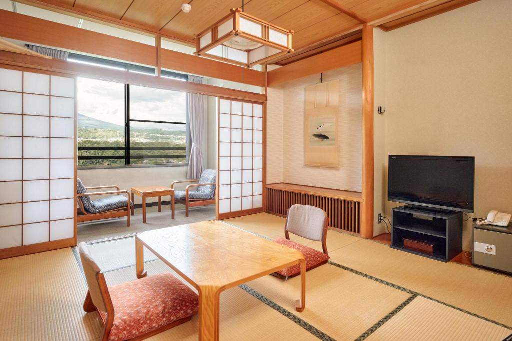 un salon avec une table et une télévision dans l'établissement Nunohiki Onsen Komoro, à Komoro