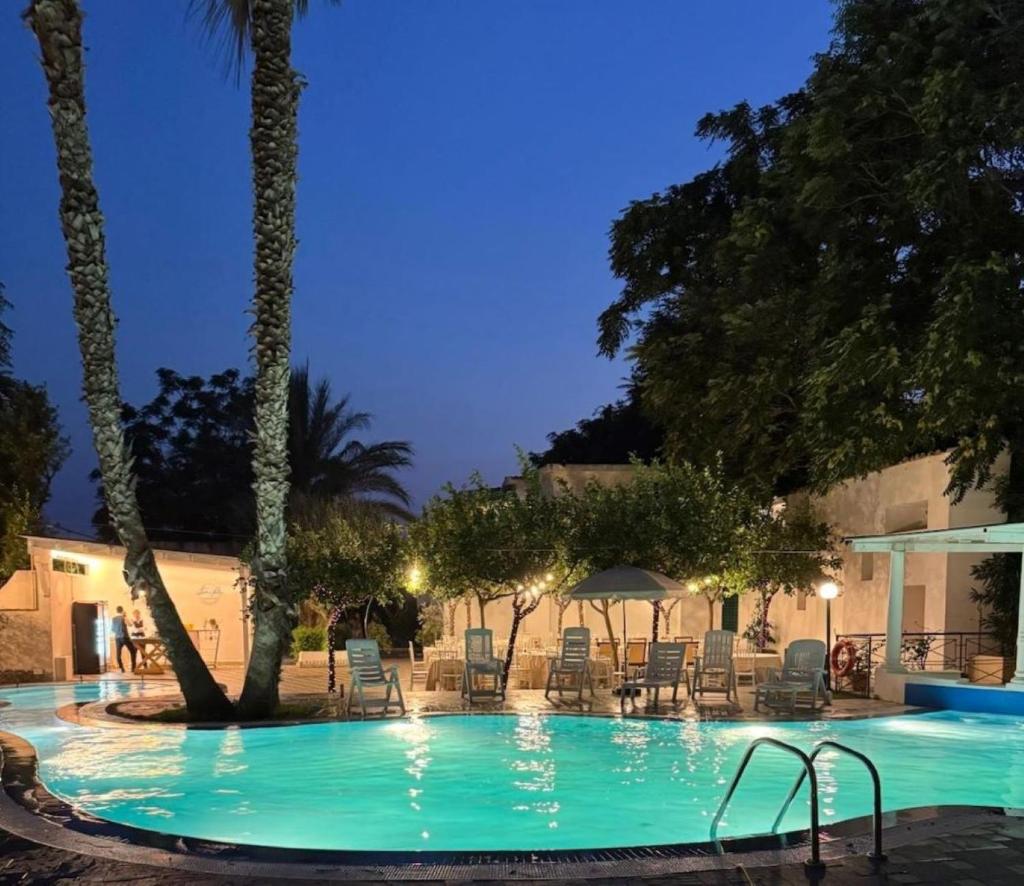 - une piscine avec des chaises et des arbres la nuit dans l'établissement Regent Beachotel, à Reggio de Calabre