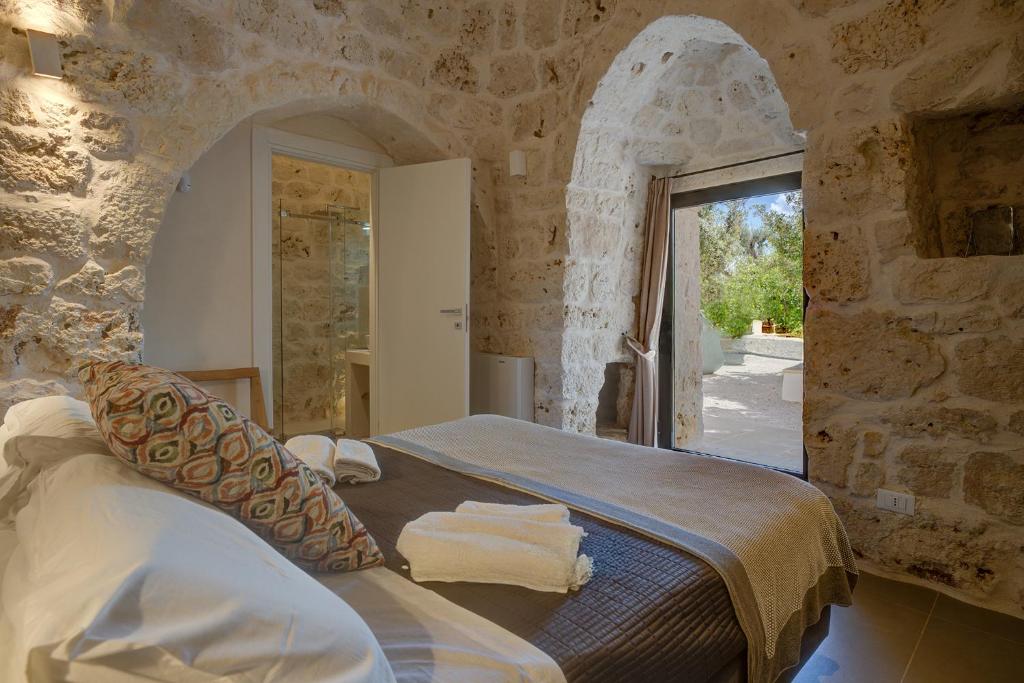 une chambre avec un lit dans un mur de pierre dans l'établissement LaCasa Puglia, à Ceglie Messapica 60 autres photos