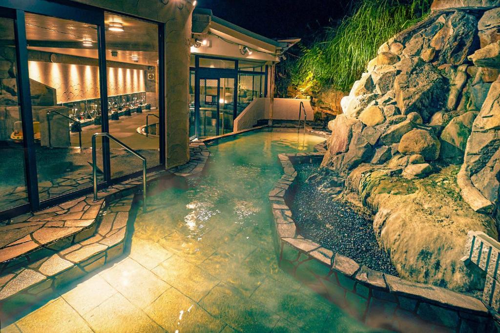 une piscine dans une maison avec un mur en pierre dans l'établissement Ooedo Onsen Monogatari Premium Shirahama Gyoen, à Shirahama
