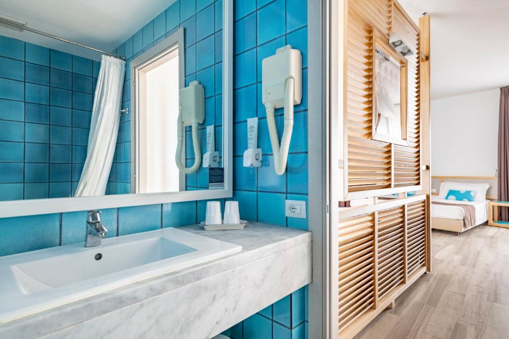une salle de bain bleue avec un lavabo et un miroir dans l'établissement Hotel Baia di Conte, à Alghero
