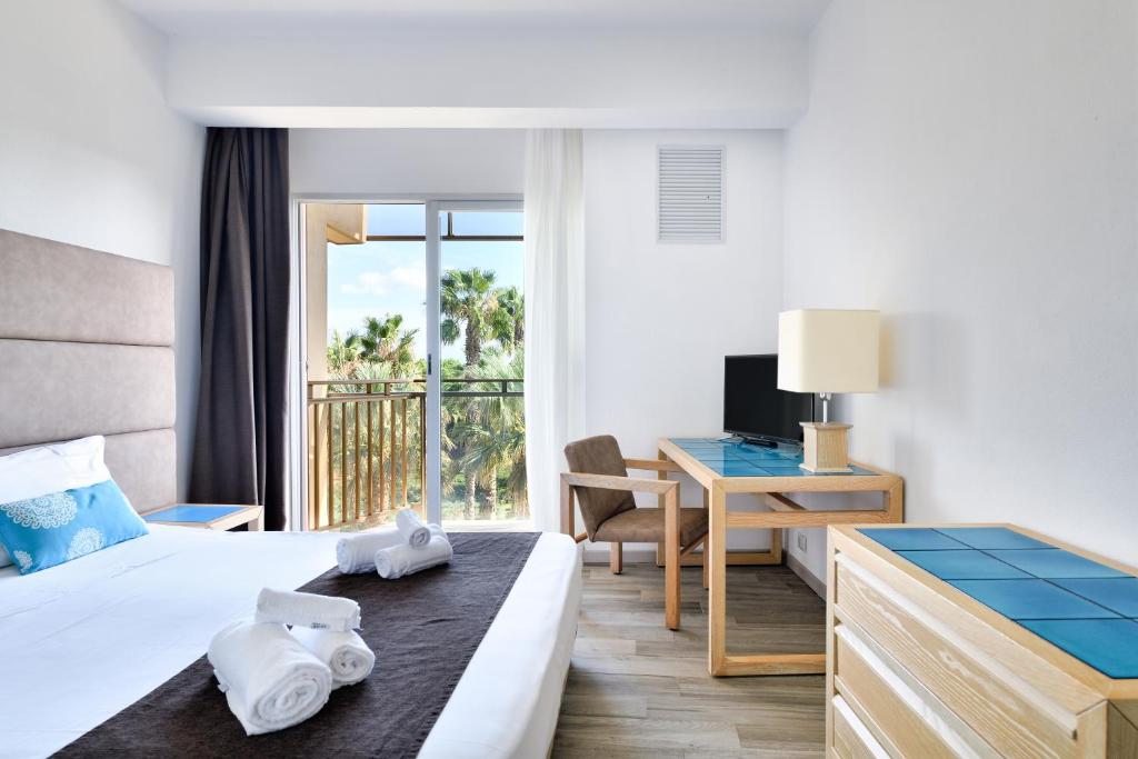 une chambre d'hôtel avec un lit et un bureau avec un ordinateur dans l'établissement Hotel Baia di Conte, à Alghero