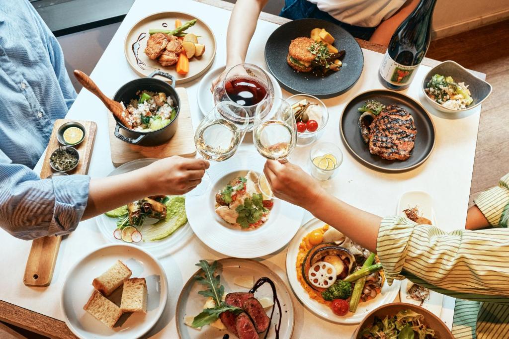Un groupe de personnes assises autour d'une table avec des assiettes de nourriture dans l'établissement WPÜ HOTEL HAKONE, à Hakone