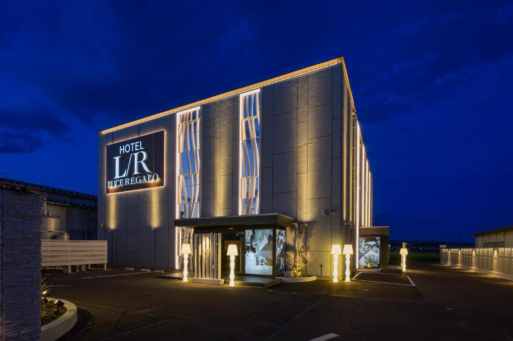 un grand bâtiment avec un panneau dessus la nuit dans l'établissement ホテルLuce Regaloｰルーチェレガーロ, à Rifu