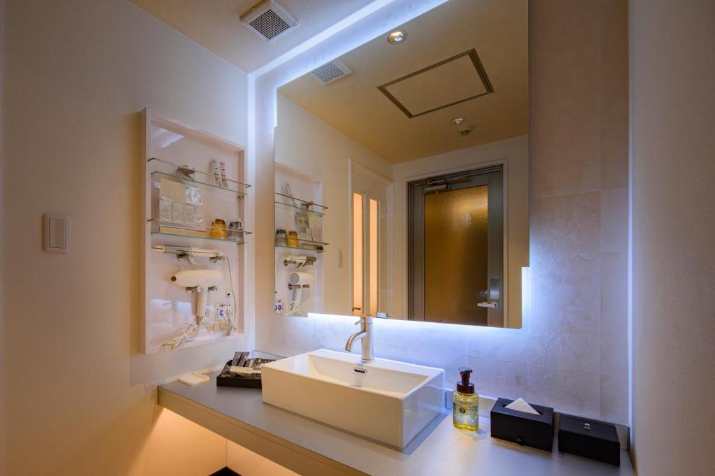 une salle de bain avec un lavabo et un miroir dans l'établissement ホテルLuce Regaloｰルーチェレガーロ, à Rifu