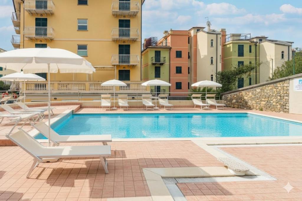 une piscine avec chaises et parasols à côté d'un bâtiment dans l'établissement Residenza al Porto, à Spotorno