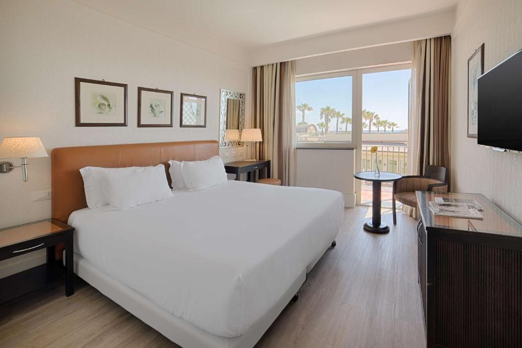 une chambre d'hôtel avec un grand lit et une télévision dans l'établissement NH Catania Parco degli Aragonesi, à Catane