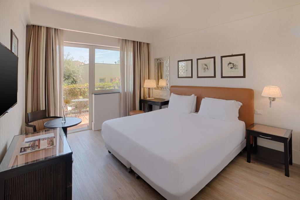 une chambre avec un grand lit blanc et un balcon dans l'établissement NH Catania Parco degli Aragonesi, à Catane 43 autres photos