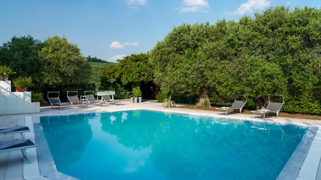 une grande piscine avec des chaises et des arbres dans l'établissement VILLA DEGLI ULIVI 8, Emma Villas, à Vérone