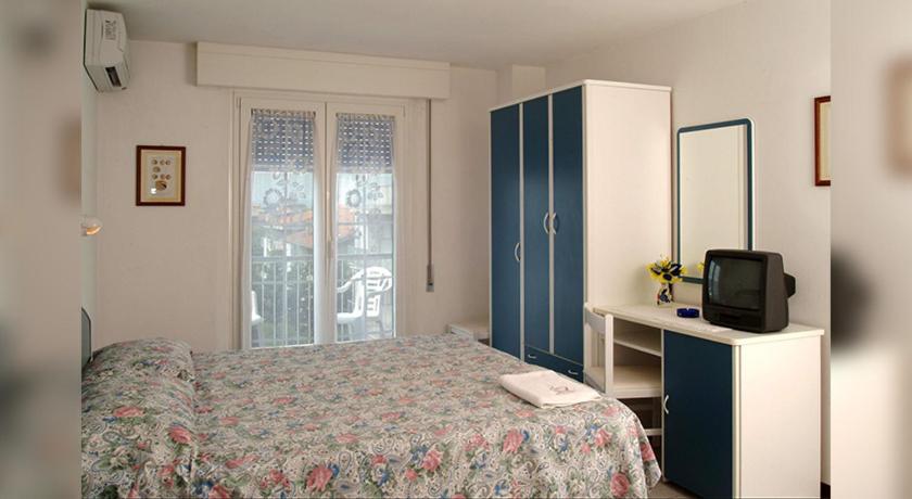 - une chambre avec un lit et une commode avec une télévision dans l'établissement Hotel Wilma, à Rimini