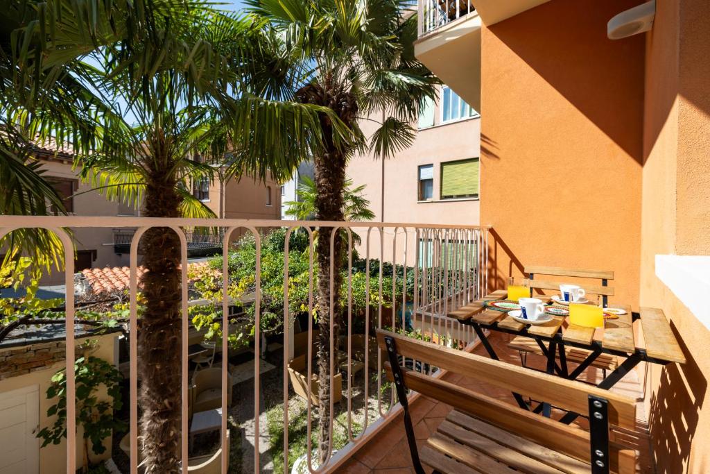 d'un balcon avec une table, une chaise et des palmiers. dans l'établissement Hotel La Pergola di Venezia, sur le Lido de Venise