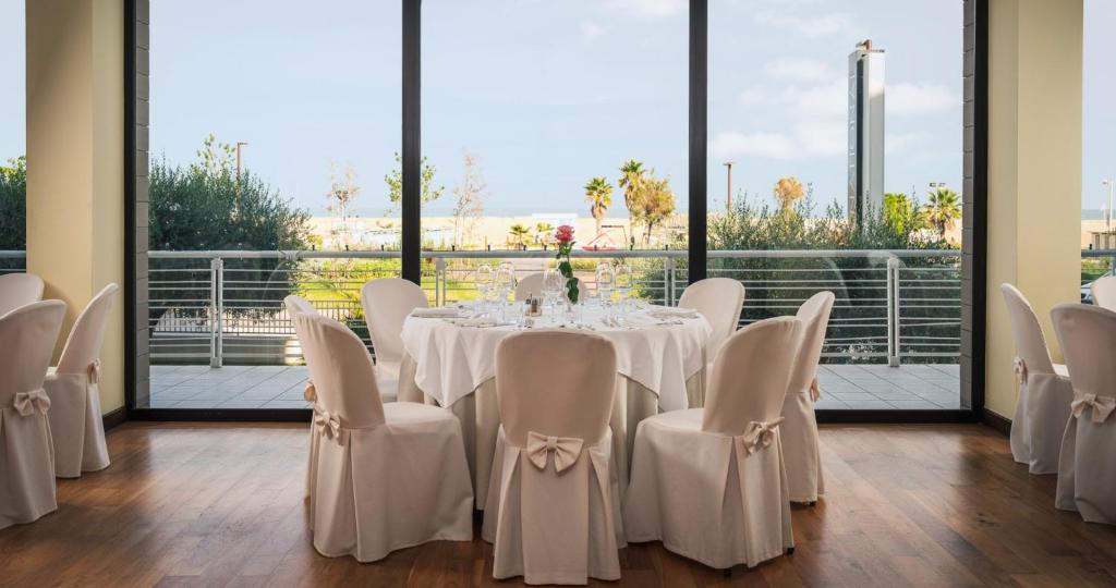 - une salle à manger avec une table, des chaises et de grandes fenêtres dans l'établissement National Hotel, à Rimini