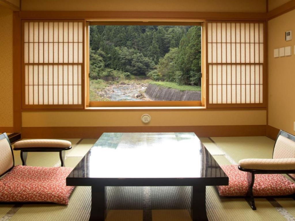 une pièce avec une table et deux chaises et une fenêtre dans l'établissement Harumiya Ryokan, à Fukushima