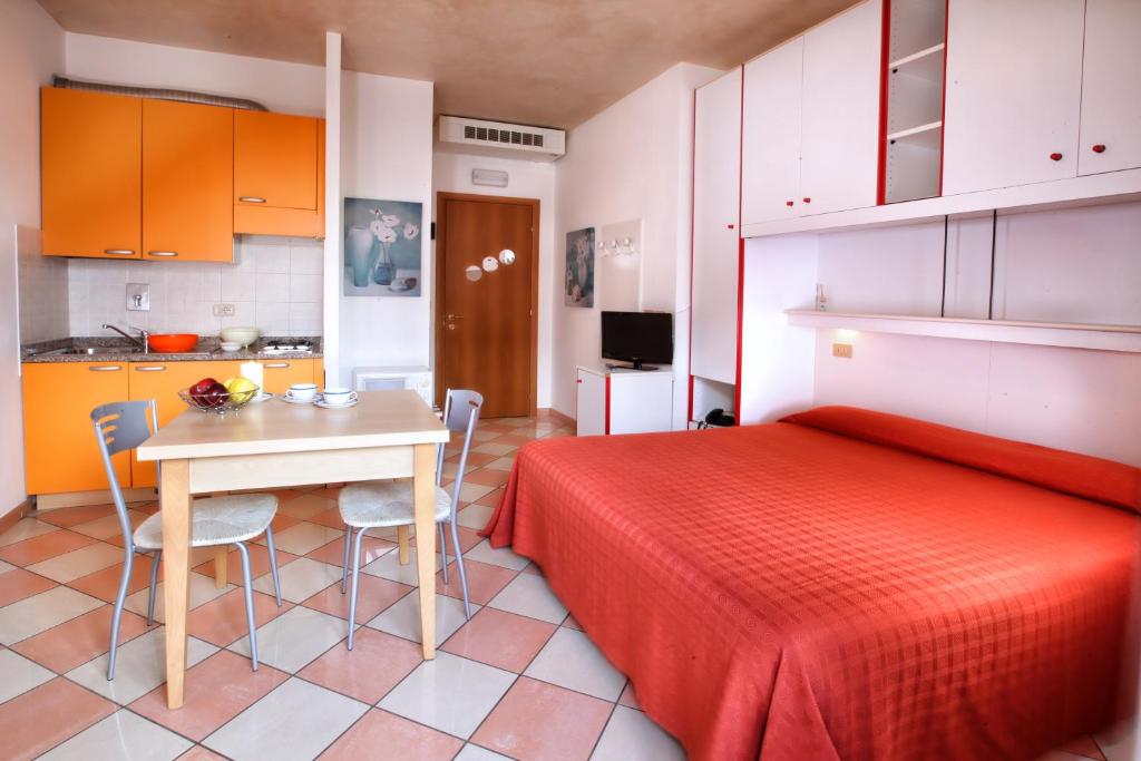 - une chambre avec un lit rouge, une table et des chaises dans l'établissement Daina Residence, à Lido di Jesolo