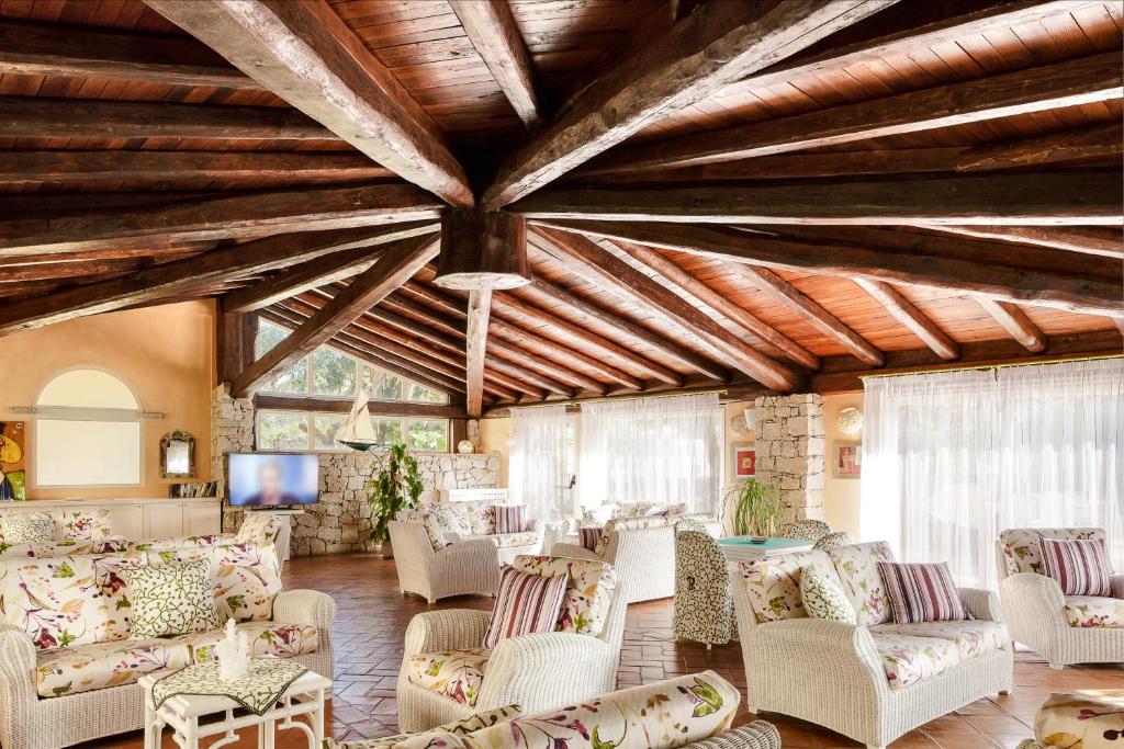 - un salon avec des canapés, des chaises et une télévision dans l'établissement Hotel Stella Maris, à Villasimius