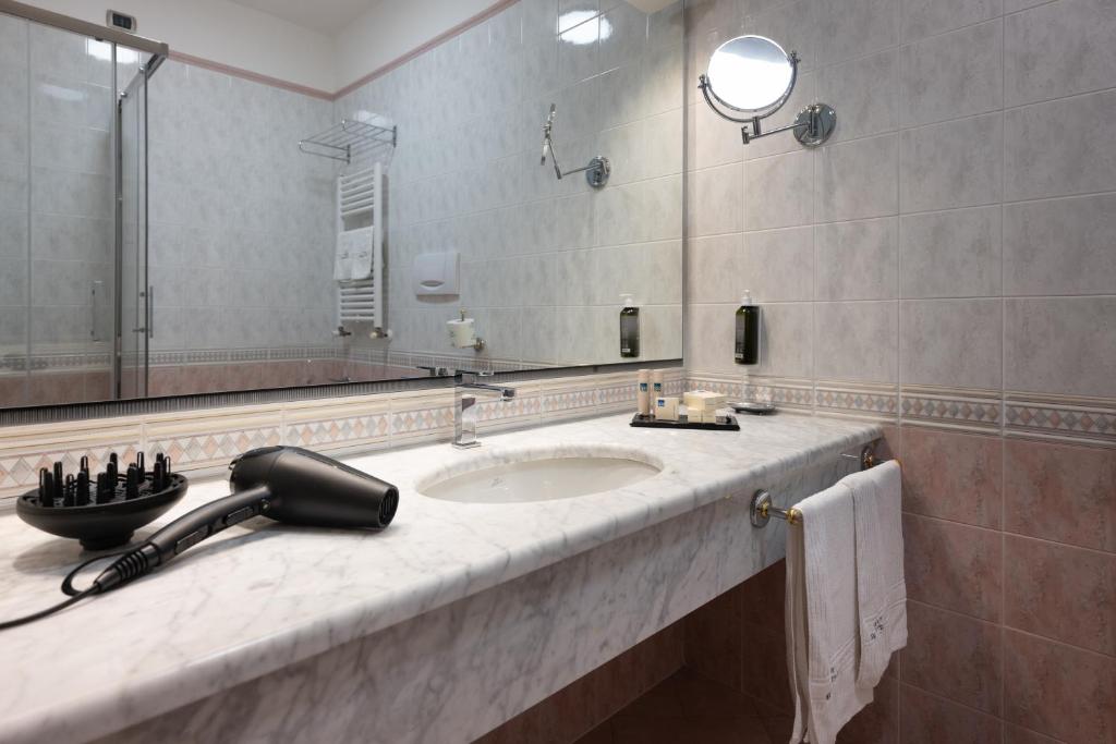 une salle de bain avec un lavabo et un miroir dans l'établissement Savoy Beach Hotel & Thermal Spa, à Bibione