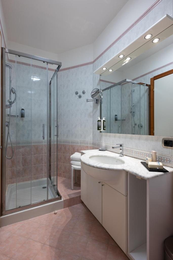 une salle de bains avec douche, lavabo et miroir dans l'établissement Savoy Beach Hotel & Thermal Spa, à Bibione