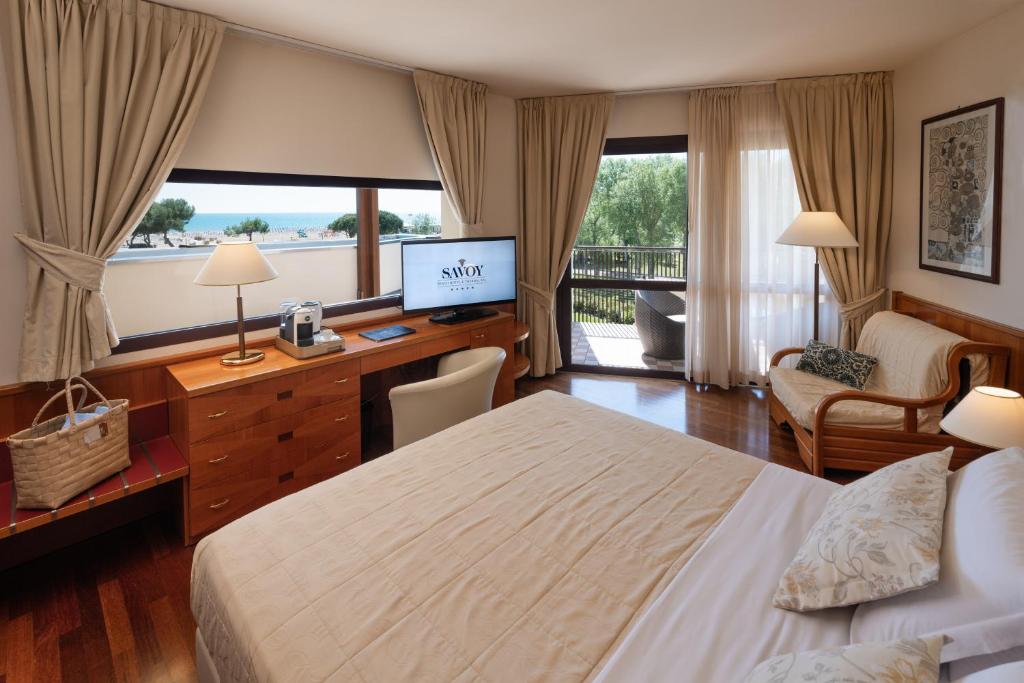 une chambre d'hôtel avec un lit et un bureau avec une télévision dans l'établissement Savoy Beach Hotel & Thermal Spa, à Bibione
