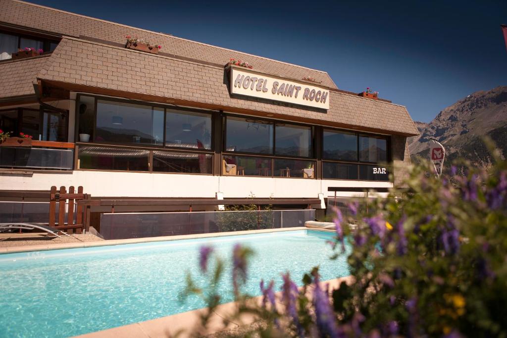 un hôtel avec une piscine devant un immeuble dans l'établissement Hôtel Restaurant Saint Roch, à Puy-Saint-Vincent
